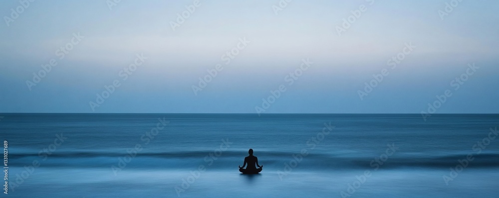 Fototapeta premium A silhouetted person sits meditating in the tranquil ocean water