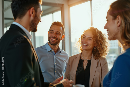 Group of four people engaged in a conversation in an office setting.