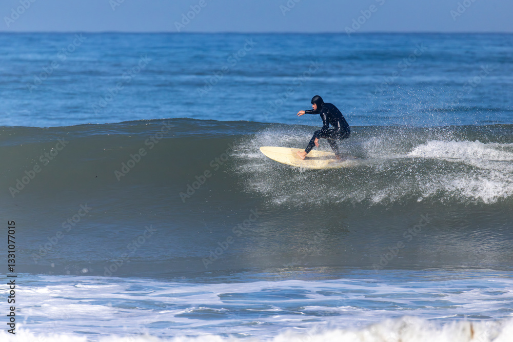 A highly skilled surfer expertly rides an enormous wave, demonstrating the exhilarating thrill of surfing against the breathtaking backdrop of a gorgeous ocean beneath a clear and vibrant blue sky A highly skilled surfer expertly rides an enormous wave, demonstrating the exhilarating thrill of surfing against the breathtaking backdrop of a gorgeous ocean beneath a clear and vibrant blue sky