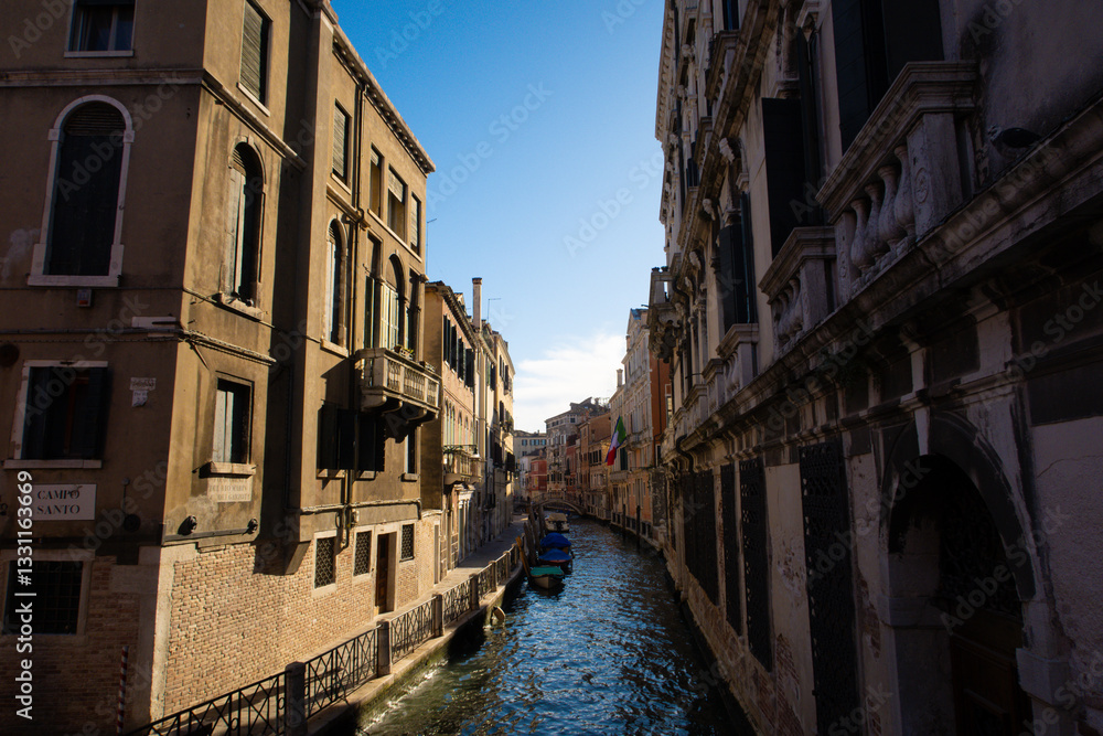 Fototapeta premium Sunlit Canal with Historic Buildings in Venice, Italy 