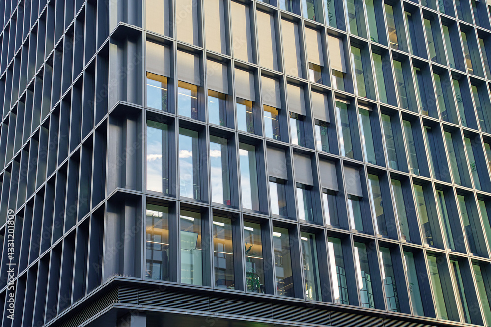 Modern office building with glass and metal facade. Corporate high rise building with geometric design and reflective windows. Contemporary architecture in urban business district