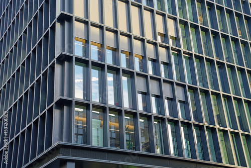 Obraz na płótnie Modern office building with glass and metal facade. Corporate high rise building with geometric design and reflective windows. Contemporary architecture in urban business district w salonie