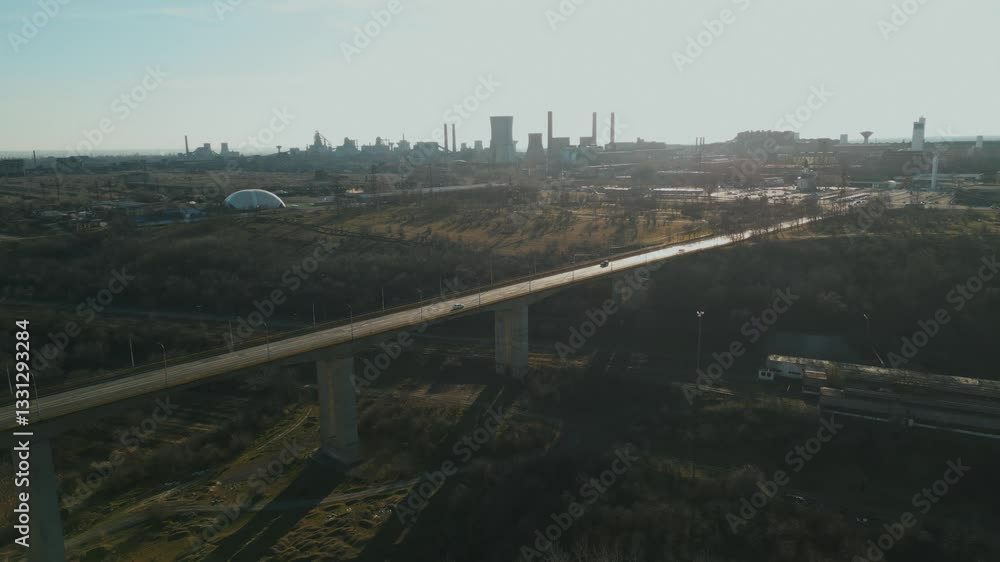 Vehicles Driving At Viaduct Bridge In Galati, Romania. Steel Manufacturing Plant In Background. wide drone shot Vehicles Driving At Viaduct Bridge In Galati, Romania. Steel Manufacturing Plant In Background. wide drone shot