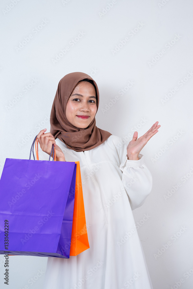 Beautiful young asian muslim woman holding shopping bags on isolated white studio background Beautiful young asian muslim woman holding shopping bags on isolated white studio background