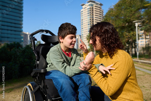 Happy child with disability communicating with special needs educator outdoors - cerebral palsy concept