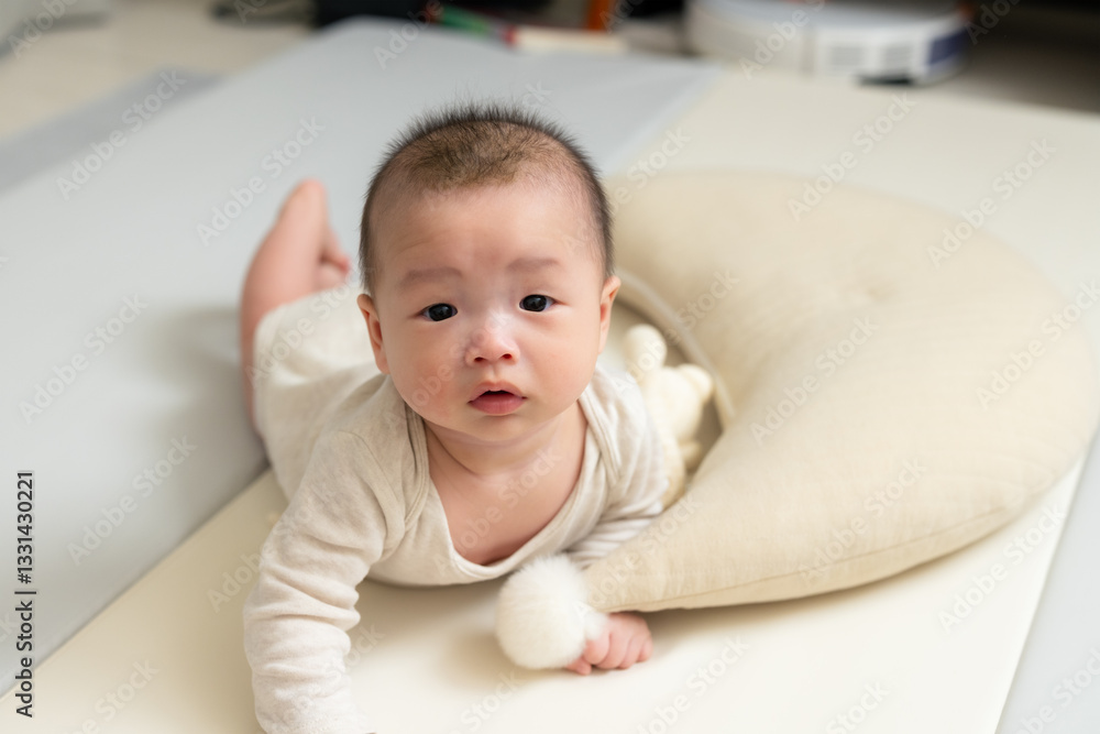 Cute baby doing tummy time on cushion