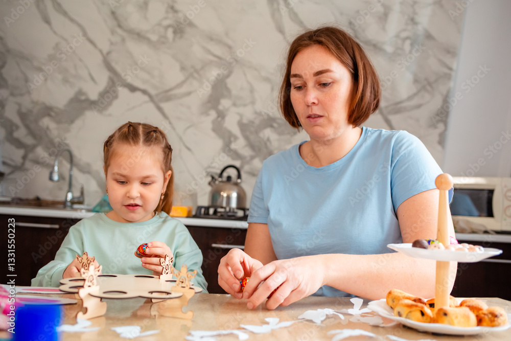 Fototapeta premium Mid shot of Caucasian mother and a little daughter are preparing for the holiday by decorating eggs for the Easter spring