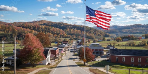 Small American town with a prominent United States flag flying against a bright autumn landscape, showcasing colorful foliage, rolling hills, and a clear blue sky