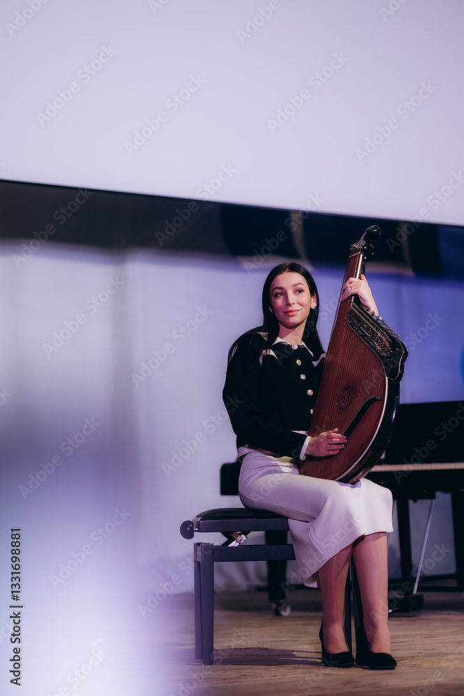 Fototapeta premium Young Musician Holding a Plucked String Instrument on Stage in Performance