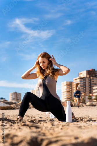 Young ukrainian woman practicing yoga on the beach, breathing and stretching