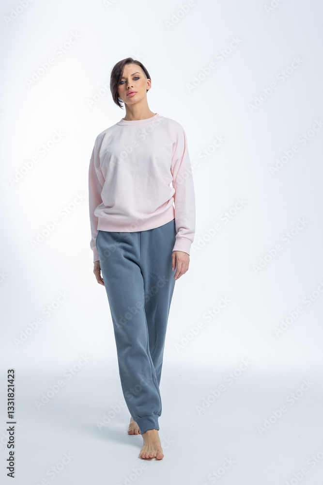 Beautiful woman of model appearance. Girl in light pink jumper and gray trousers on light background. Pretty female with trendy makeup posing in studio. Vertical photo. High quality photo Beautiful woman of model appearance. Girl in light pink jumper and gray trousers on light background. Pretty female with trendy makeup posing in studio. Vertical photo. High quality photo