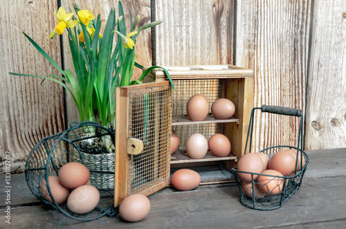 chicken eggs  in little metal baskets and a decorative box on a table with a ...