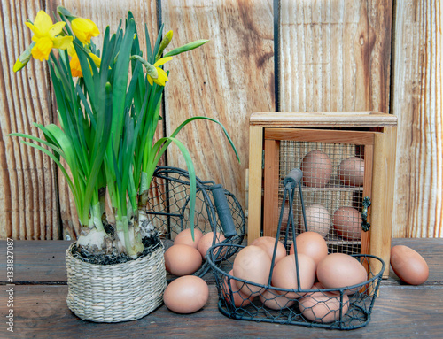 chicken eggs  in little metal baskets and decorative box on a table in front ...