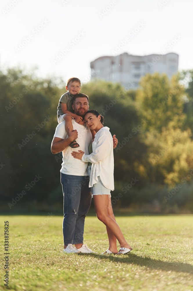 Three people. Mother and father are with son outdoors on the field Three people. Mother and father are with son outdoors on the field