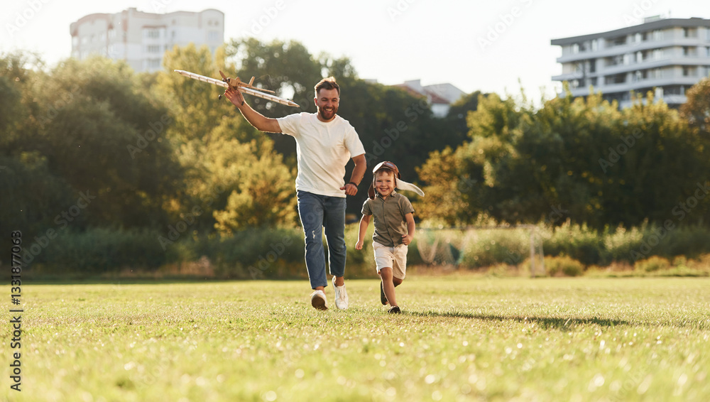 Fototapeta premium Active weekend, running. Father and son are on the field together with toy plane