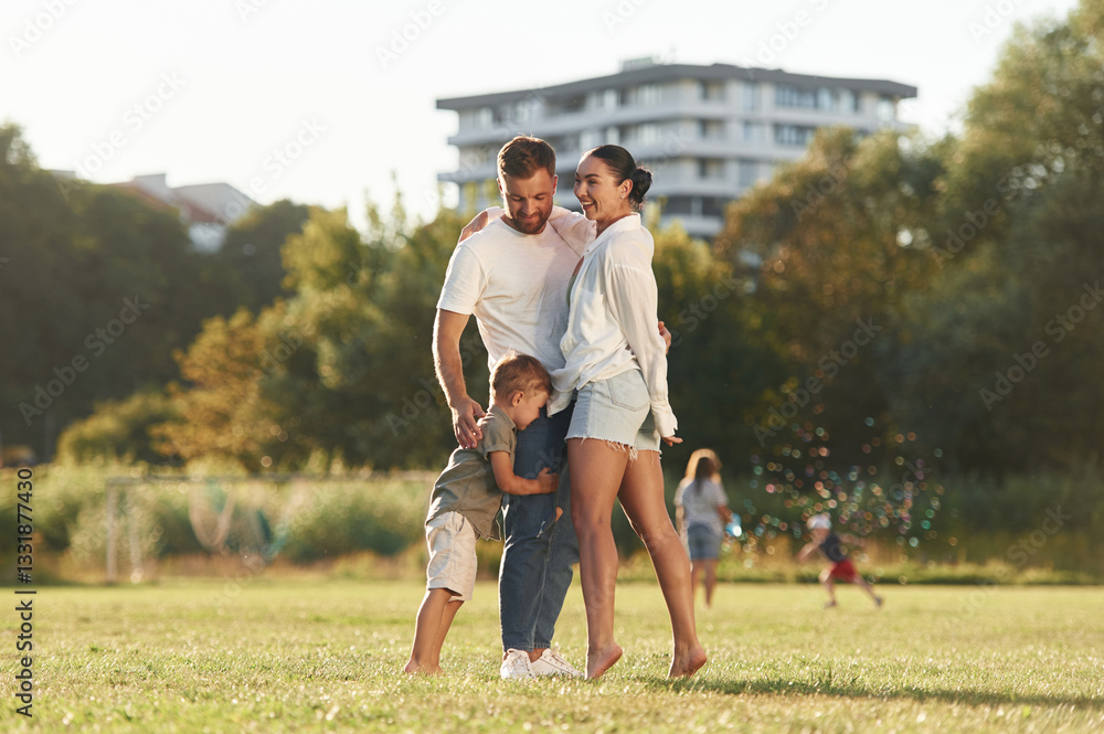 Obraz premium Closeness, embracing. Mother and father are with son outdoors on the field