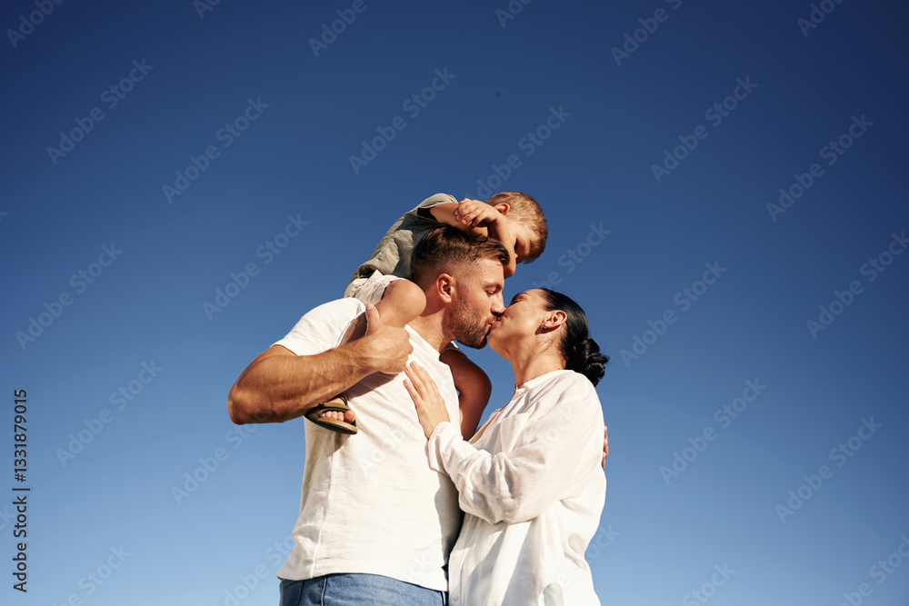 Bright blue sky, against it. Mother and father are with son outdoors on the field Bright blue sky, against it. Mother and father are with son outdoors on the field