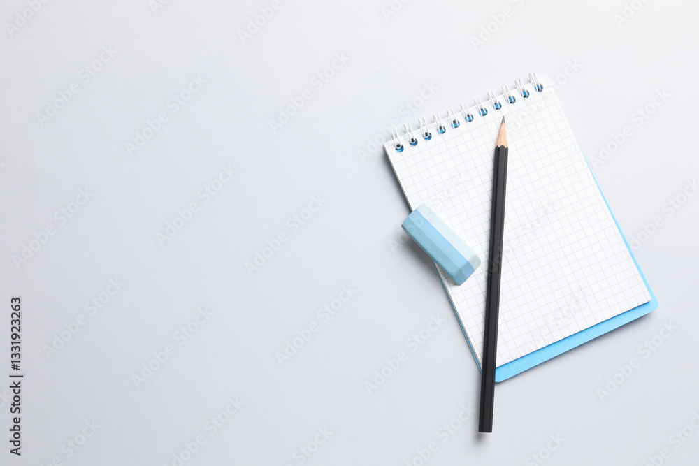 Eraser, pencil and notepad on light background, top view. Space for text Eraser, pencil and notepad on light background, top view. Space for text