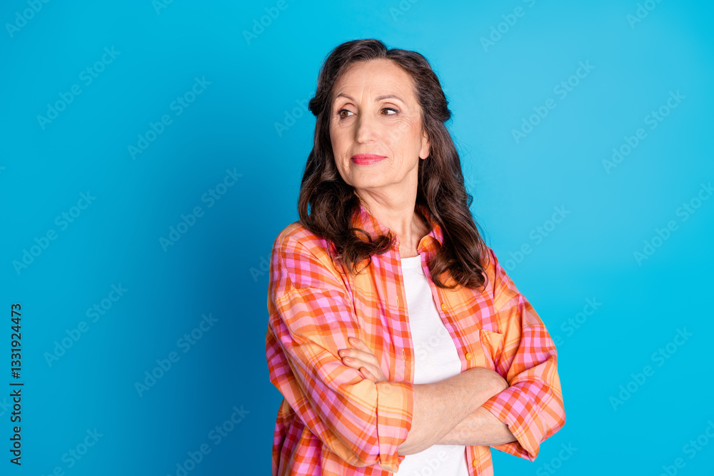 Portrait of a Fashionable Mature Woman in a Checkered Shirt Standing Confidently on a Blue Background Portrait of a Fashionable Mature Woman in a Checkered Shirt Standing Confidently on a Blue Background