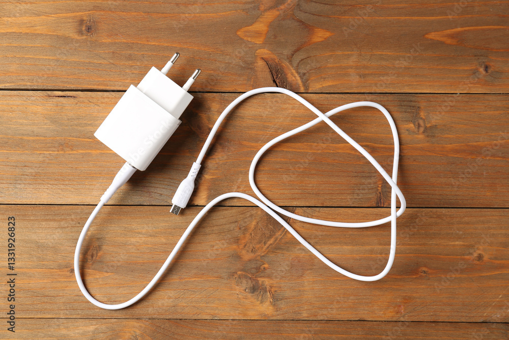 USB power adapter with charge cable on wooden table, top view USB power adapter with charge cable on wooden table, top view