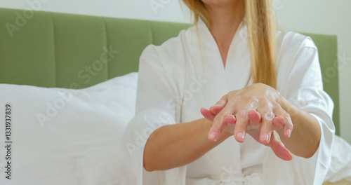 Wallpaper Mural Woman in Bathrobe Applying Lotion on Hands While Sitting in Bedroom Torontodigital.ca