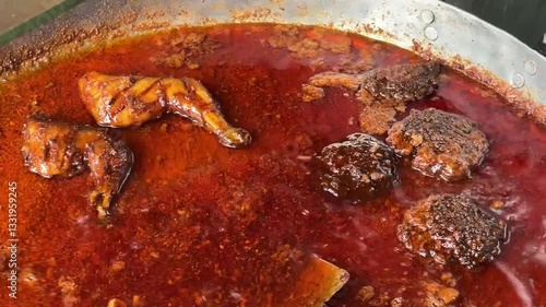 A big hot vessel containing oily, spicy mutton and chicken chap.