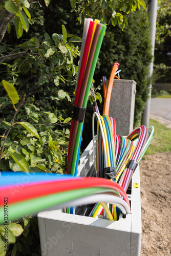 Offene Glasfaser-Verteilerbox mit bunten Glasfaser-Rohren – Breitbandausbau in Wohngebieten, modernes Telekommunikationsnetz für Highspeed-Internet und Digitalisierung.