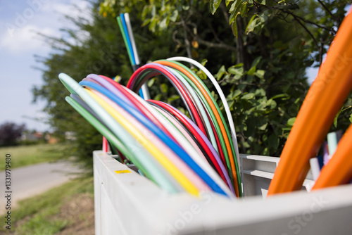 Offene Glasfaser-Verteilerbox mit bunten Glasfaser-Rohren – Breitbandausbau in Wohngebieten, modernes Telekommunikationsnetz für Highspeed-Internet und Digitalisierung.