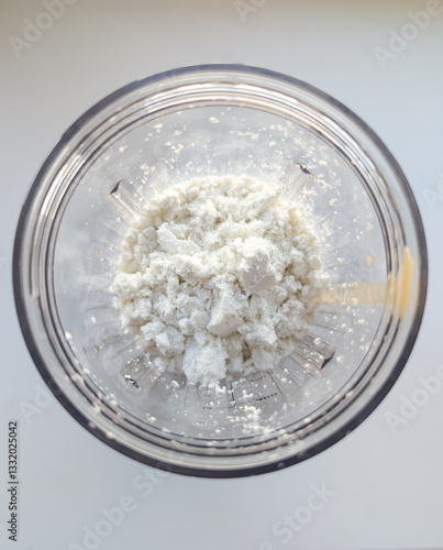 Close-up of white protein powder with added nut oil in a clear plastic shaker, ready to mix into a healthy sports drink.