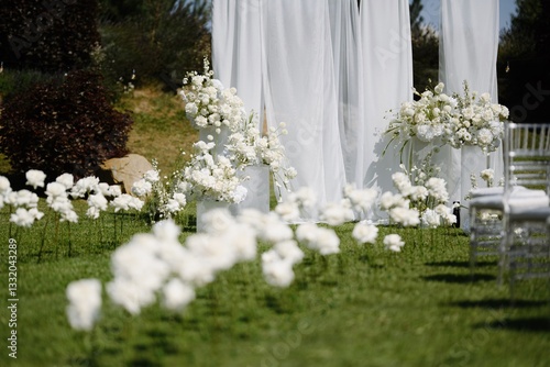 Elegant outdoor wedding setup with white flowers and sheer drapes