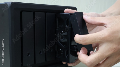 Fotografía close up of someone's hand inserting a hard disk into a Network Attached Storage