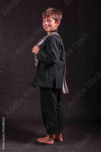 laughing boy in a black kimono with a gray belt draped over his shoulder
