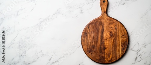 A wooden circular board sits atop a white stone kitchen table, captured from a bird's eye view in a flat lay style, accompanied by a wooden round pizza serving tray that leaves space for text