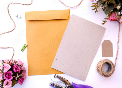 Brown envelope and blank brown greeting card with flowers bouquet on white background.