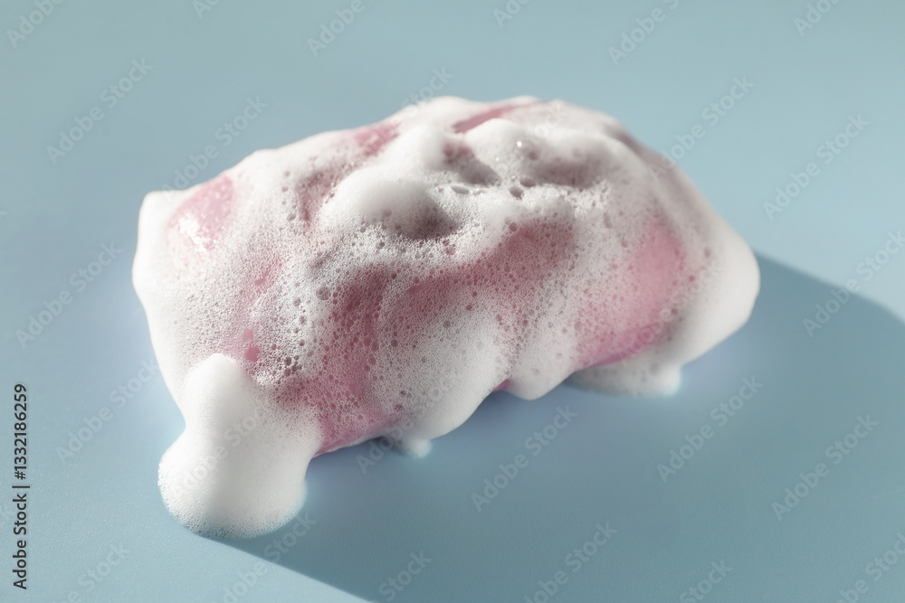 Fototapeta premium Soap bar with foam on grayish blue background, closeup
