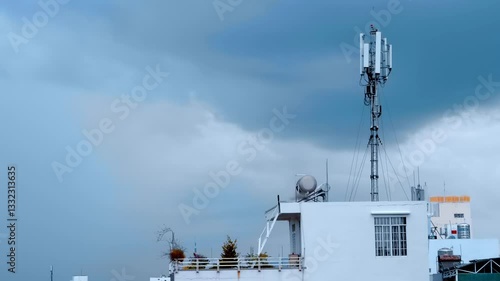 Mobile telecommunication tower in the city on the background of cloudy rainy sky. A dragonfly slowly flies in front of the camera. Slow mo, slow motion, high speed camera, 200fps