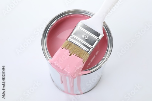 Can of pink paint and brush on white background