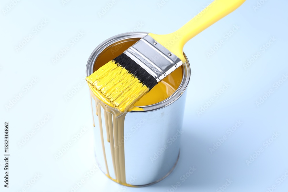 Can of yellow paint and brush on light background Can of yellow paint and brush on light background