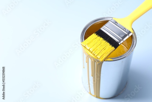 Can of yellow paint and brush on light background. Space for text