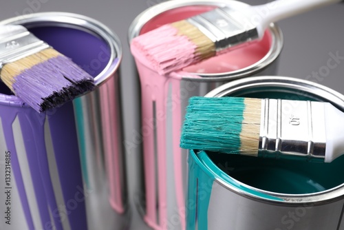 Cans of paint and brushes on grey background, closeup