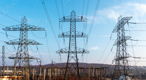 High voltage power lines stretch across the landscape under a clear blue sky, showcasing the infrastructure of electrical transmission