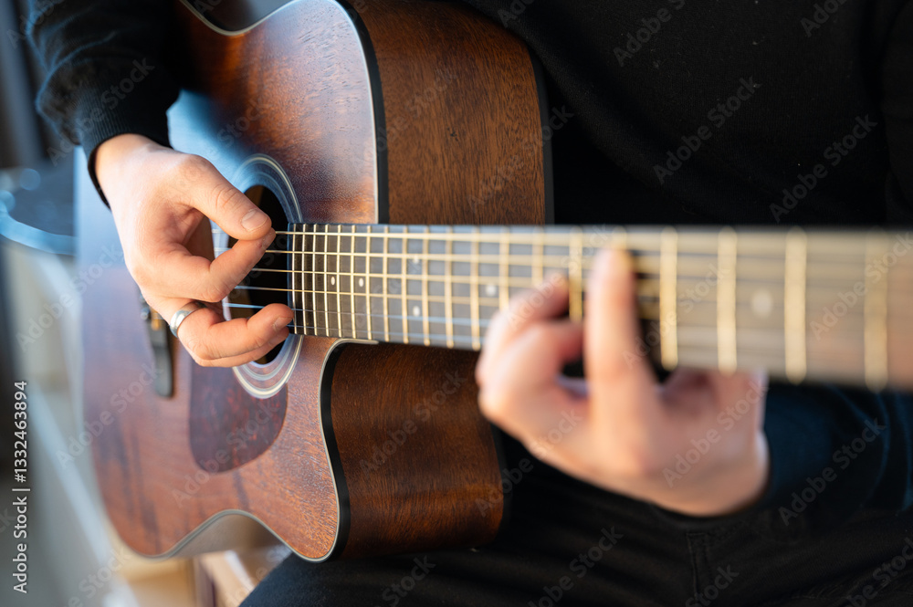 Fototapeta premium Skilled hands expertly play an acoustic guitar in beautiful natural light, showcasing artistry