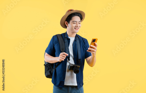 Portrait of young asian man traveling and using phone on yellow background