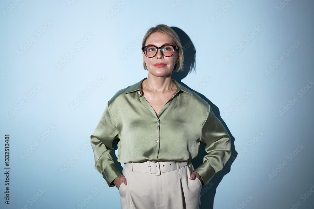 Portrait of elegant businesswoman standing on blue background and looking at camera Portrait of elegant businesswoman standing on blue background and looking at camera