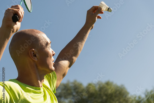 Man playing badminton on green sport court in public park. Outdoors. Summer sports game. Copy space. Close up.