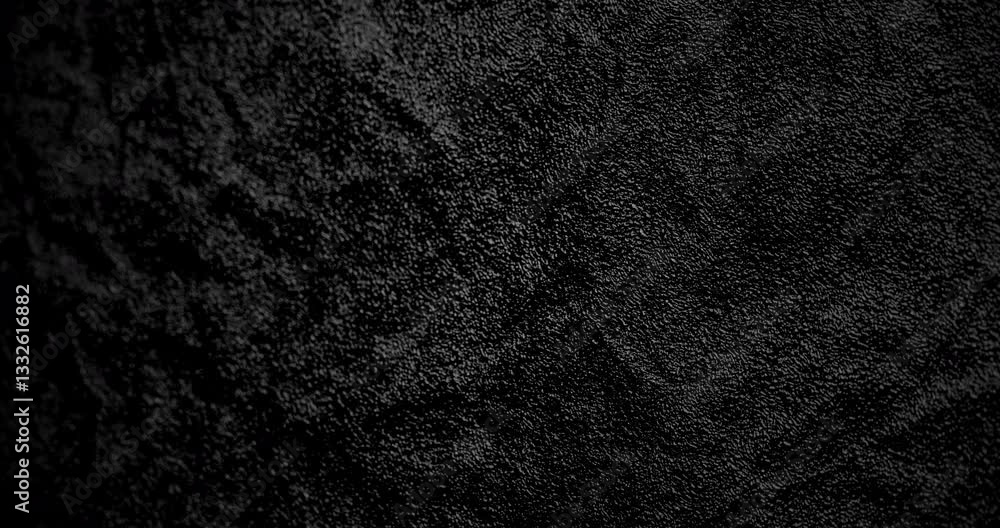 Dark Textured Surface with Subtle Motion. A close-up of a dark textured surface with subtle rotational motion, creating a sleek and modern effect.