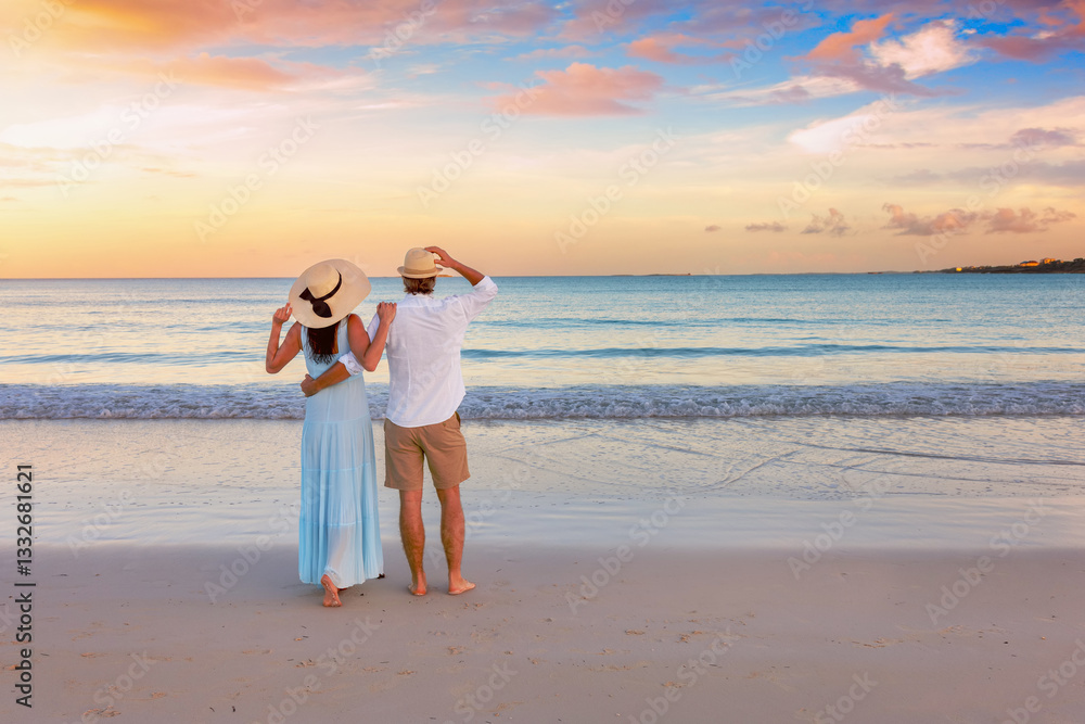 A hugging, romantic couple on vacation stands on a tropical paradise beach during beautiful sunset time