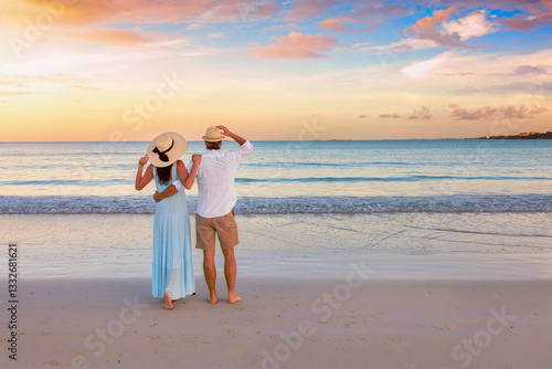 Obraz na płótnie A hugging, romantic couple on vacation stands on a tropical paradise beach during beautiful sunset time w salonie
