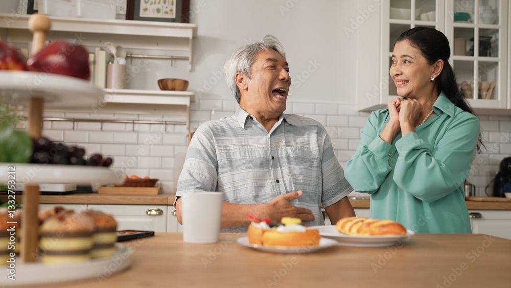 Smiling grandfather with casual cloth sitting at table while grandmother presenting breakfast. Senior couple talking and spending time or supporting together. Healthy relationship concept. Myrmidon. Smiling grandfather with casual cloth sitting at table while grandmother presenting breakfast. Senior couple talking and spending time or supporting together. Healthy relationship concept. Myrmidon.