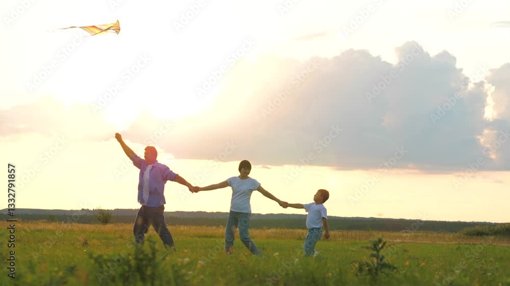 Family playing with flying kite holding hands at sunset grass wheat field outdoor leisure. Happy mother father and son relaxing enjoy freedom lifestyle weekend activity at meadow nature landscape Family playing with flying kite holding hands at sunset grass wheat field outdoor leisure. Happy mother father and son relaxing enjoy freedom lifestyle weekend activity at meadow nature landscape